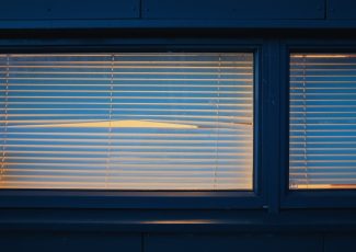 empty window with blinds and peephole at night