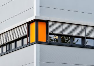 Horizontal shot of a grey building with open windows and grey window blinds