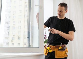 Master in gloves adjusting pvc windows with screwdriver closeup. Installation of plastic windows